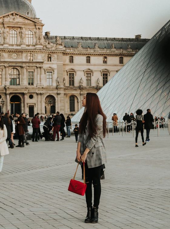 une-femme-avec-un-sac-a-main-rouge-de-createur-en-face-de-la-pyramide-du-louvre-a-Paris